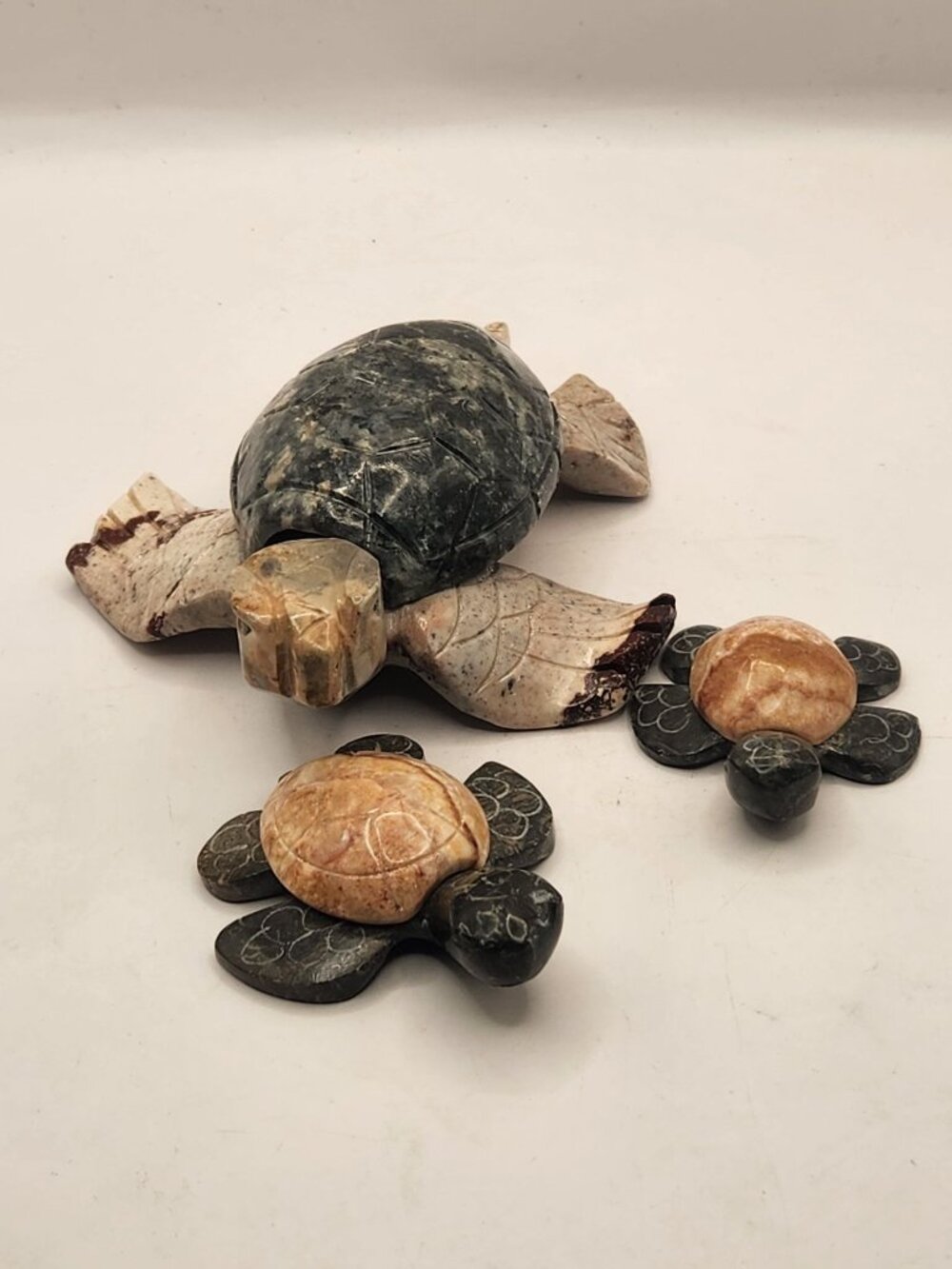 3 hand-carved stone sea turtles figurine made from tan soapstone and a dark gree